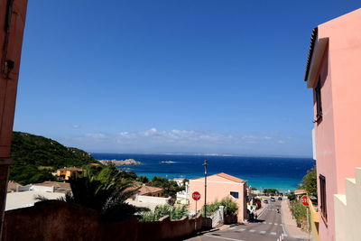 Buildings by sea against clear blue sky