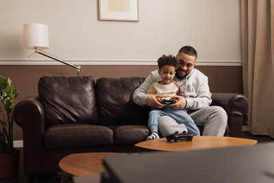 Cheerful father and son playing game at home