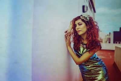 Portrait of beautiful young woman standing against wall