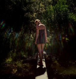 Woman standing on tree trunk