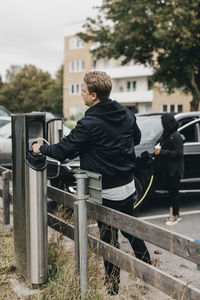 Man connecting cable at electric car charging station