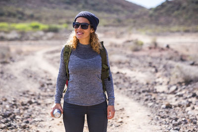 Young woman wearing sunglasses standing on land