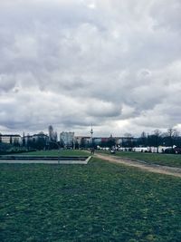 View of field against cloudy sky