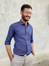 Smiling young man standing against wall