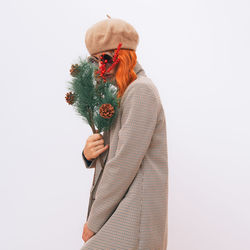 Portrait of woman holding flowers against white background