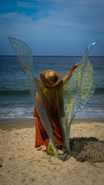 Woman with umbrella on beach against sky