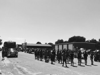 Group of people on road against clear sky