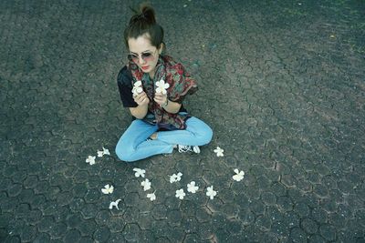 High angle view of girl sitting on footpath