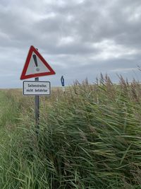 Road sign on field against sky