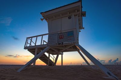 Low angle view of lifeguard hut on beach against sky during sunset