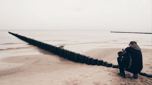 Rear view of man looking at sea against sky