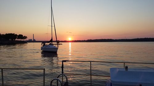 Silhouette boats sailing in sea against sky during sunset