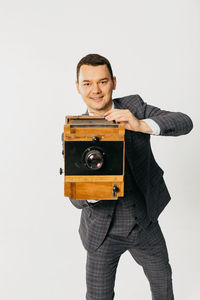 Portrait of young man photographing against white background