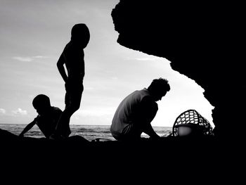 Silhouette men on beach against sky during sunset