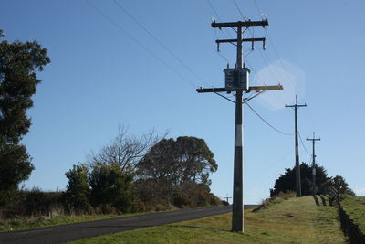 Low angle view of electricity pylon on field against clear sky