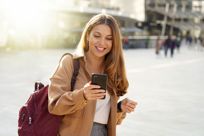 Smiling woman using mobile phone on street