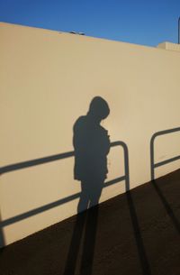 Shadow of man on railing against sky