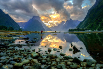 Man standing on lake against sky during sunset