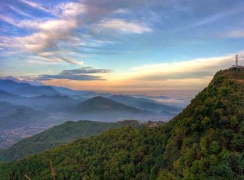 Scenic view of landscape against cloudy sky at sunset