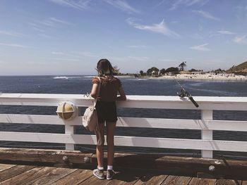 Rear view of girl looking at sea against sky