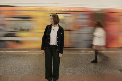 Blurred motion of train at railroad station and static girl