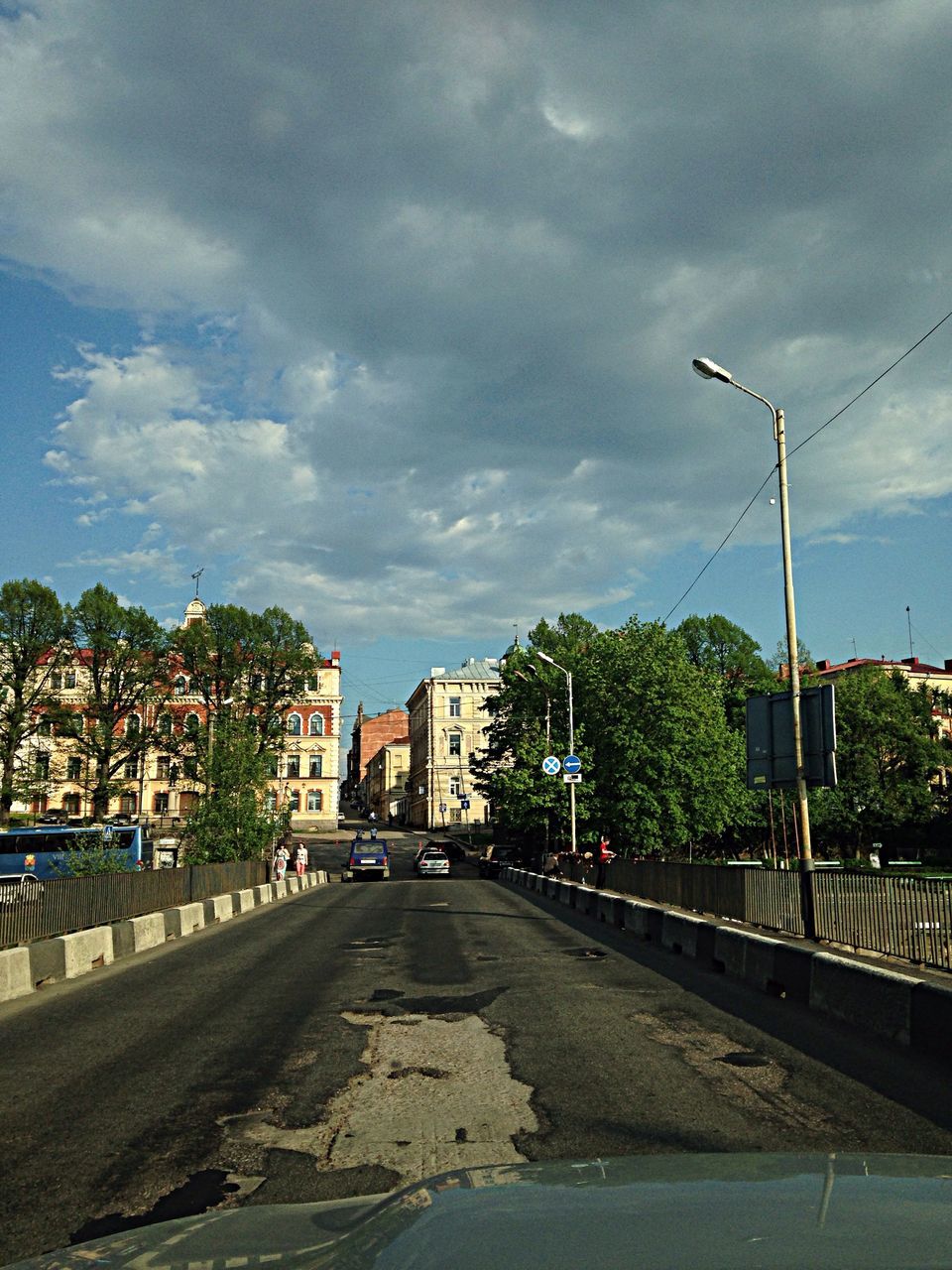 sky, building exterior, architecture, built structure, cloud - sky, street light, transportation, street, the way forward, cloudy, road, cloud, city, car, residential building, tree, residential structure, diminishing perspective, house, land vehicle