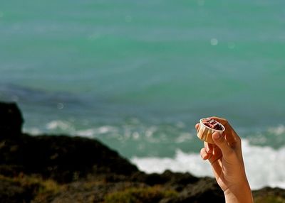 Close-up of woman hand holding sea against blurred background