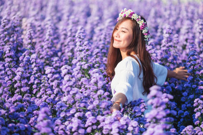 Portrait of woman standing on purple flowering plants