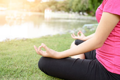 Midsection of woman sitting by lake