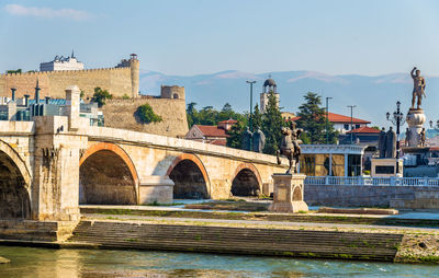 Arch bridge over river against buildings in city