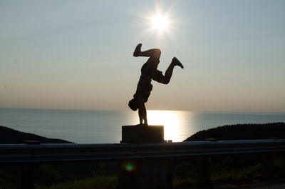Silhouette people in sea against sky during sunset