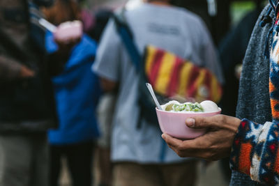 Midsection of people holding ice cream outdoors