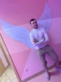 Portrait of smiling young woman against pink wall