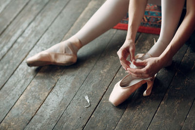 Low section of woman wearing ballet shoe