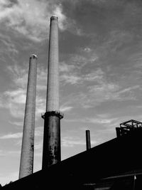 Low angle view of factory against cloudy sky