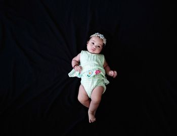 Portrait of cute girl against black background