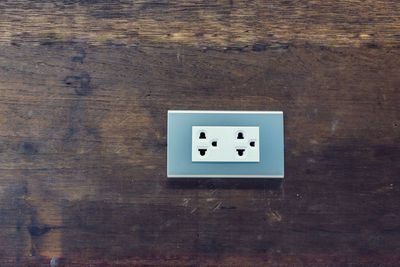 Close-up of electrical outlet on wooden wall