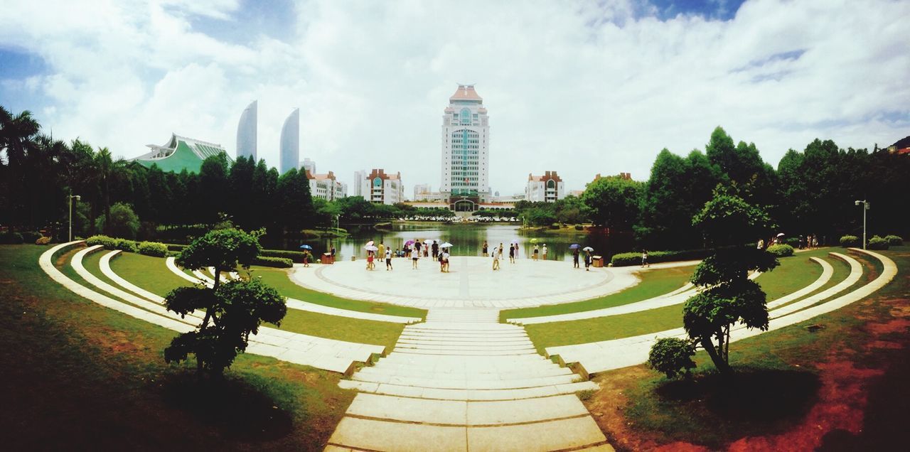 tree, building exterior, architecture, built structure, city, sky, large group of people, modern, cloud - sky, skyscraper, men, park - man made space, city life, person, tall - high, cloud, leisure activity, lifestyles, growth