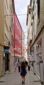 Rear view of people walking on street amidst buildings