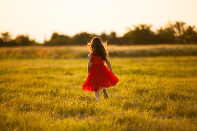 Girl walking on field against sky