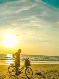 Bicycle on beach against sky during sunset