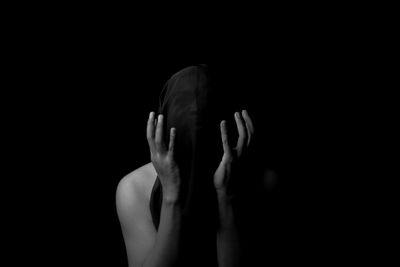 Closeup portait of man covering head in dark background