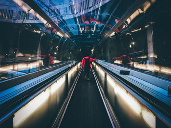 Rear view of woman walking on moving walkway