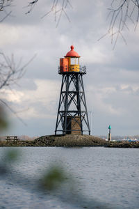 Lighthouse by sea against sky