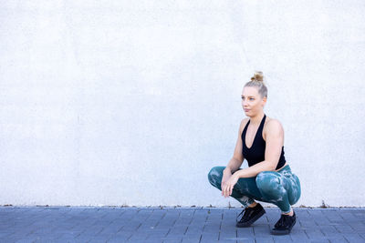 Portrait of young woman exercising against sky