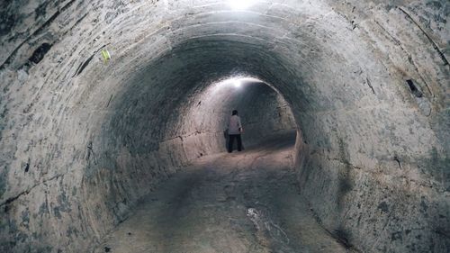 Rear view of man walking in tunnel