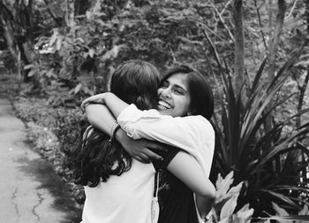 Happy friends embracing while standing by plants