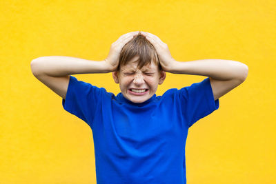 Mid adult man standing against yellow wall