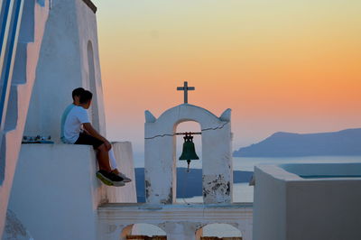 Woman standing by sea against sky during sunset