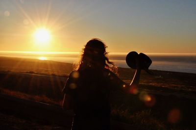 Woman standing by sea during sunset